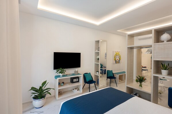 Ein modernes Schlafzimmer mit Bett, Fernseher, Kleiderschrank und Schreibtisch.