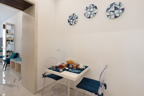 A dining area with a table set for breakfast, clear chairs, and a whiteboard on the wall. - Bed and Breakfast 'Sorrento Lux Suite' with Balcony, Wi-Fi and Air Conditioning (Sorrento)