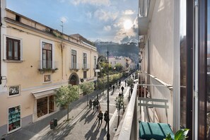 Vista de una calle con edificios, cielo despejado y una colina distante.