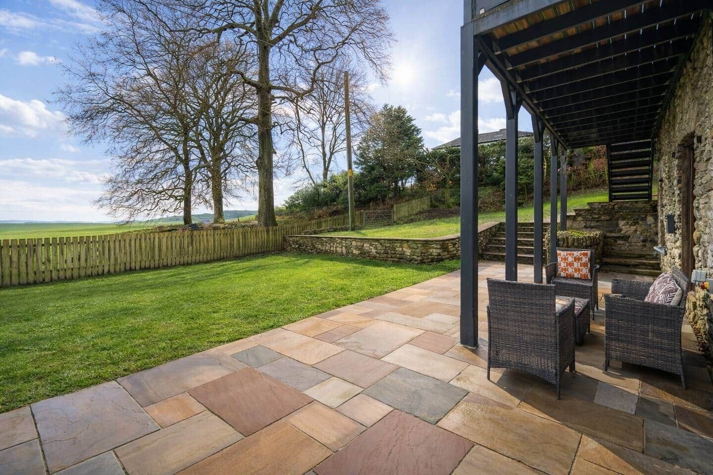 A patio area with stone flooring, wicker furniture, and a stone wall.