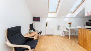 Un espacio habitable moderno y compacto con techo estilo loft, zona de comedor y kitchenette.