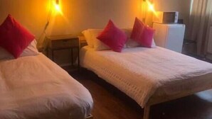 Une chambre d’hôtel avec deux lits, chacun doté d’un oreiller rouge, d’une tête de lit en bois et de lampes de chevet.