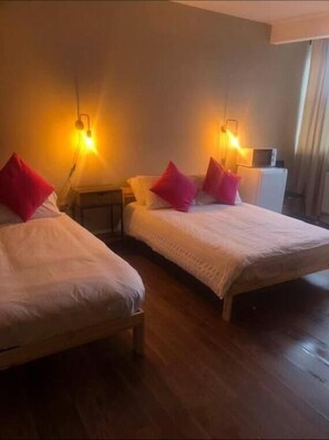 A hotel room with two beds, each with a red pillow, wooden headboards, and bedside lamps. - Izzy hotel ltd (Wallsend)