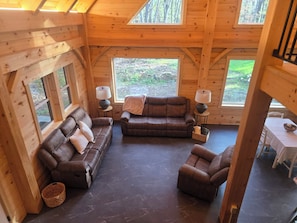 A cozy cabin interior with a leather sofa, armchair, and a dining table. - Tranquil cabin in Somerset PA (Somerset)
