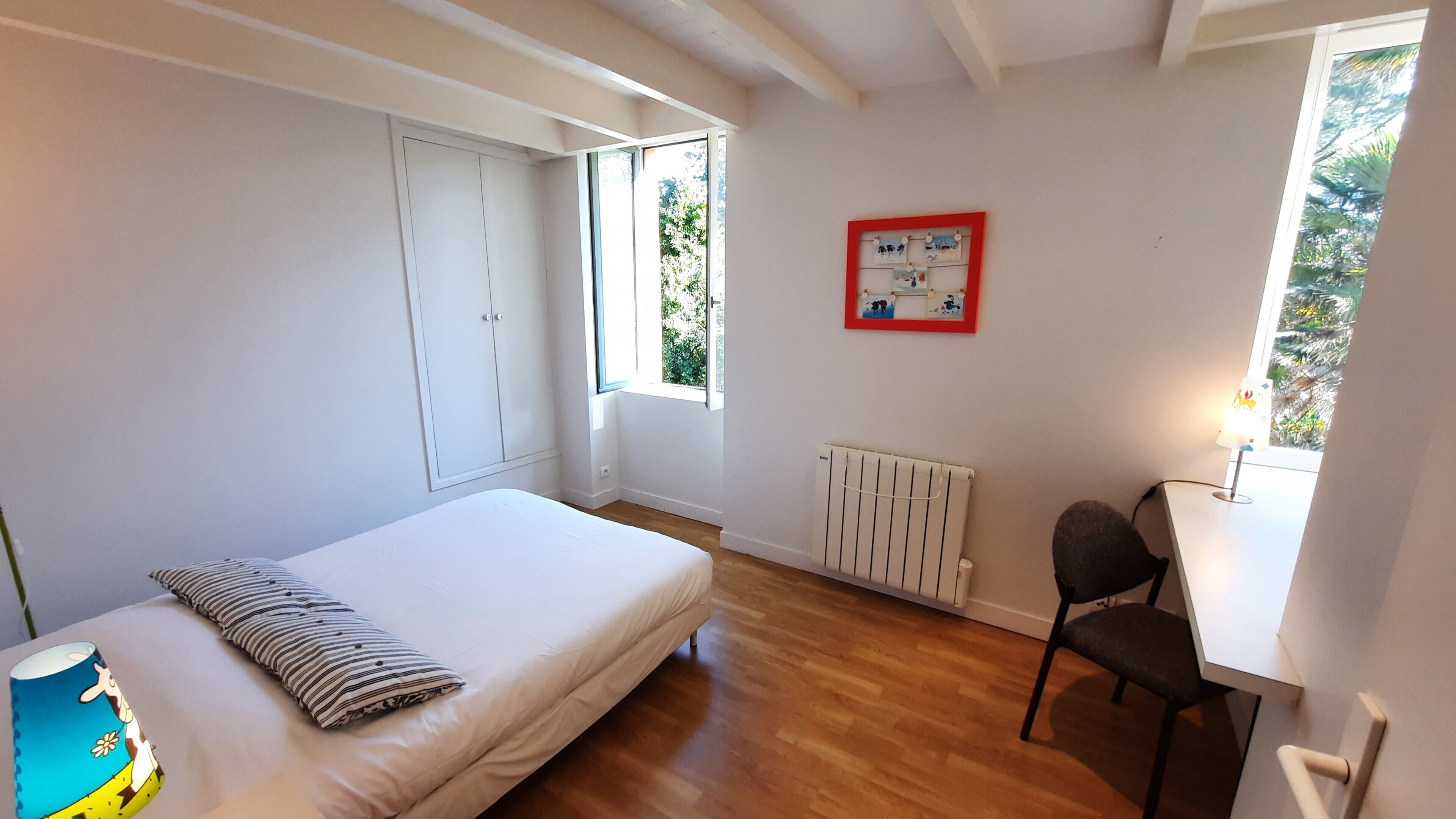 Un dormitorio con cama, una silla, un radiador y una ventana.