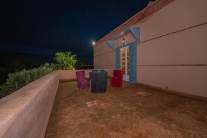 An outdoor patio area with a tiled floor, a small table, and three chairs.