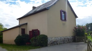 Ein eingeschossiges Gebäude mit einem geneigten Dach, einem Steinfundament und einer kleinen Veranda mit Holzzaun.
