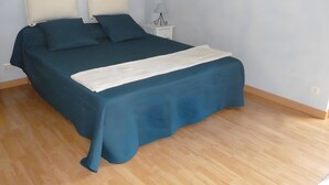 Ein Schlafzimmer mit einem Bett, Kissen, einem Nachttisch und einer Lampe.