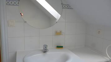 Un bagno con un lavandino bianco, uno specchio e un portascopevoli.