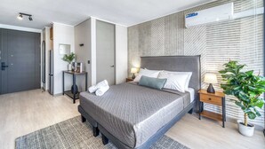 Ein modernes Schlafzimmer mit einem großen Bett, Nachttischen, einem Spiegel und einer Klimaanlage.