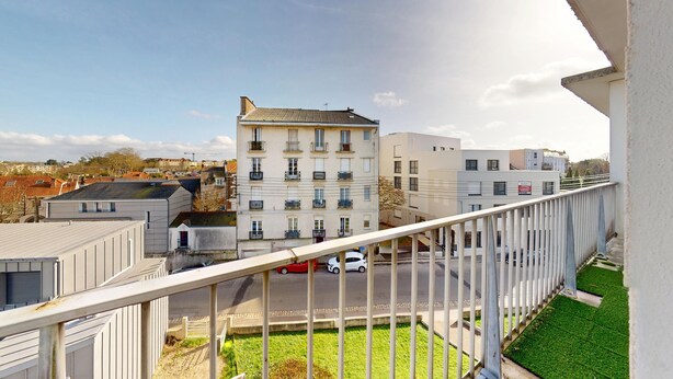 Un edificio residencial con varios balcones, un césped verde y un cielo despejado.