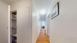 Un pasillo con piso de madera, paredes blancas y una puerta que da a un área de almacenamiento.