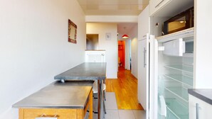 Una cocina moderna con encimera de acero inoxidable, un refrigerador blanco y un microondas.