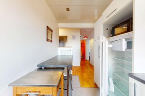 A modern kitchen with a stainless steel countertop, a white refrigerator, and a microwave. - 2BR flat with balcony 5 mn to Hippodrome de Nantes (Nantes)
