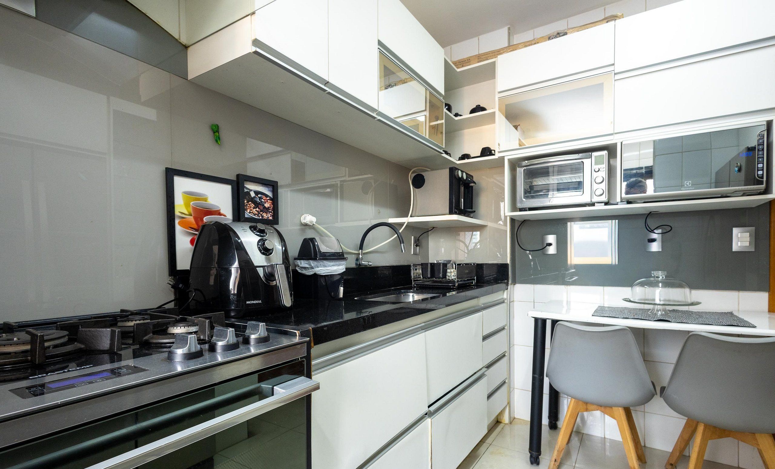 A modern kitchen with a stove, microwave, and a dining area with chairs.