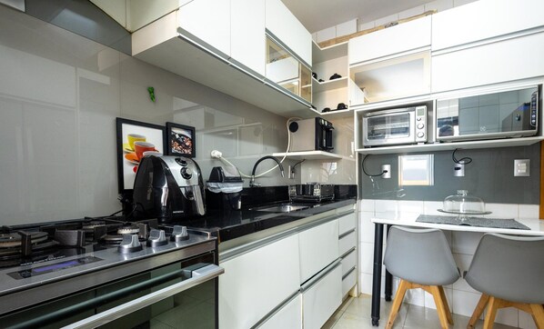 A modern kitchen with a stove, microwave, and a dining area with chairs.