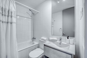 Un baño moderno con bañera, inodoro, lavabo y espejo.