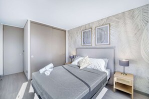 Ein modernes Schlafzimmer mit einem großen Bett, einem Nachttisch mit Lampe und einem Kleiderschrank.