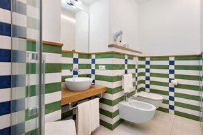 A bathroom with a glass shower enclosure, a sink with a wooden countertop, a toilet, and a bidet. - Sorrento Stylish – Deluxe Room with Balcony (Sorrento)