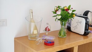 Une table en bois sur laquelle se trouvent une bouteille, un verre, un vase avec des fleurs, un grille-pain et une petite boîte rouge.