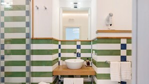 Une salle de bain avec un lavabo blanc, un miroir et un sèche-cheveux fixé au mur.
