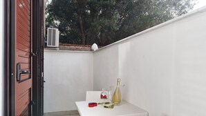 Une table blanche avec une bouteille de vin, un verre et un petit objet rouge.