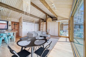 A spacious living area with a wooden ceiling, a dining table with chairs, a sofa, and a large window offering a view of the outdoors. - Bluelight Concón- Sea View w/ Wifi (Concón)