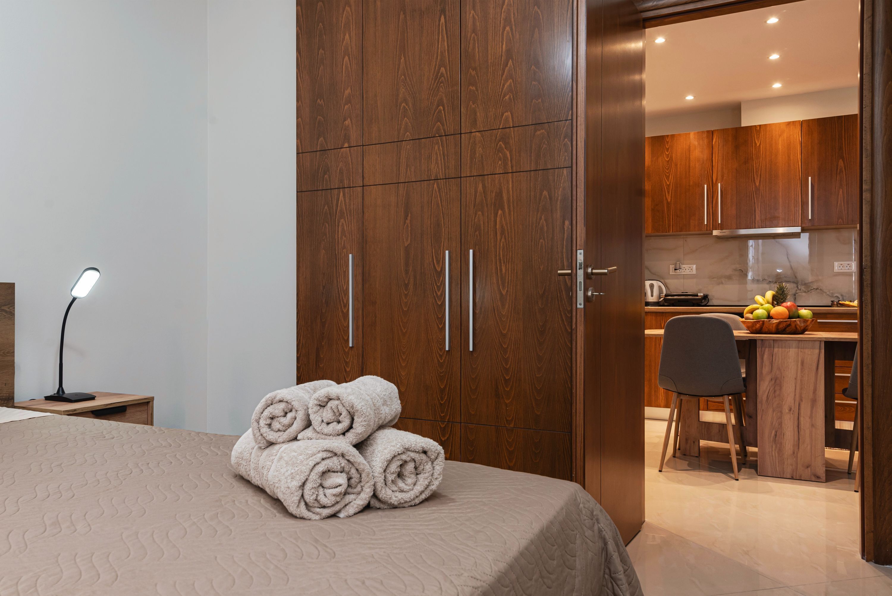 A hotel room with a bed, a desk, and a kitchenette.