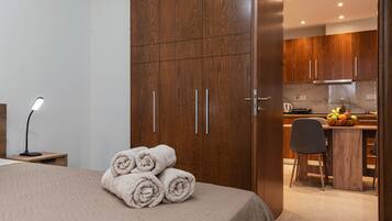 A hotel room with a bed, a desk, and a kitchenette.