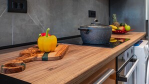 Una encimera de cocina con una tabla de cortar de madera, un pimiento amarillo, una olla y un frutero.