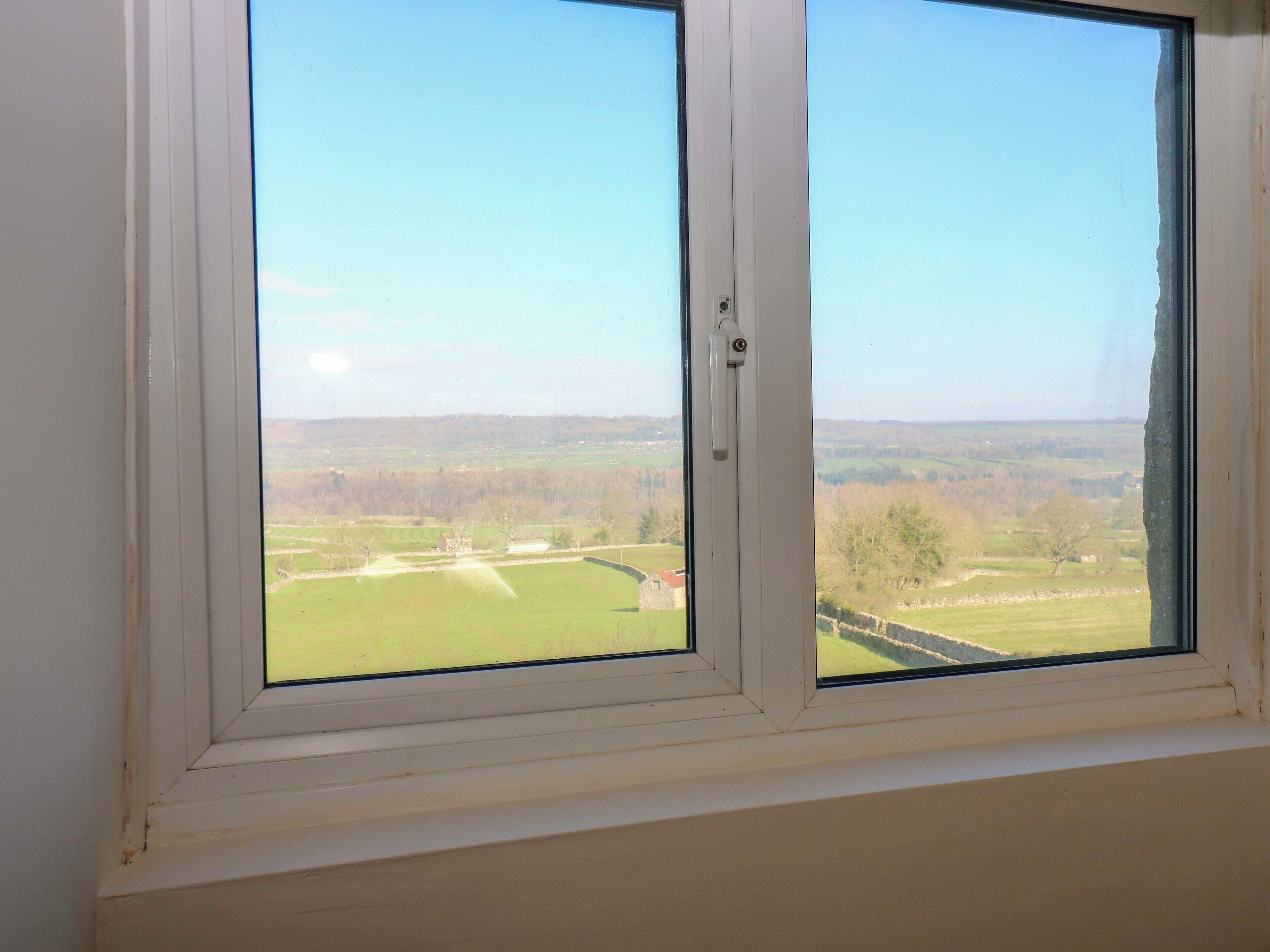 Una ventana con vistas a un paisaje verde y un cielo despejado.