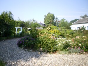 A gravel path leading through a garden with various plants and a white structure. - Maison Le Clos des Ânes: private terrace and garden in Sainte-Marguerite sur Duclair (Sainte-Marguerite-sur-Duclair)