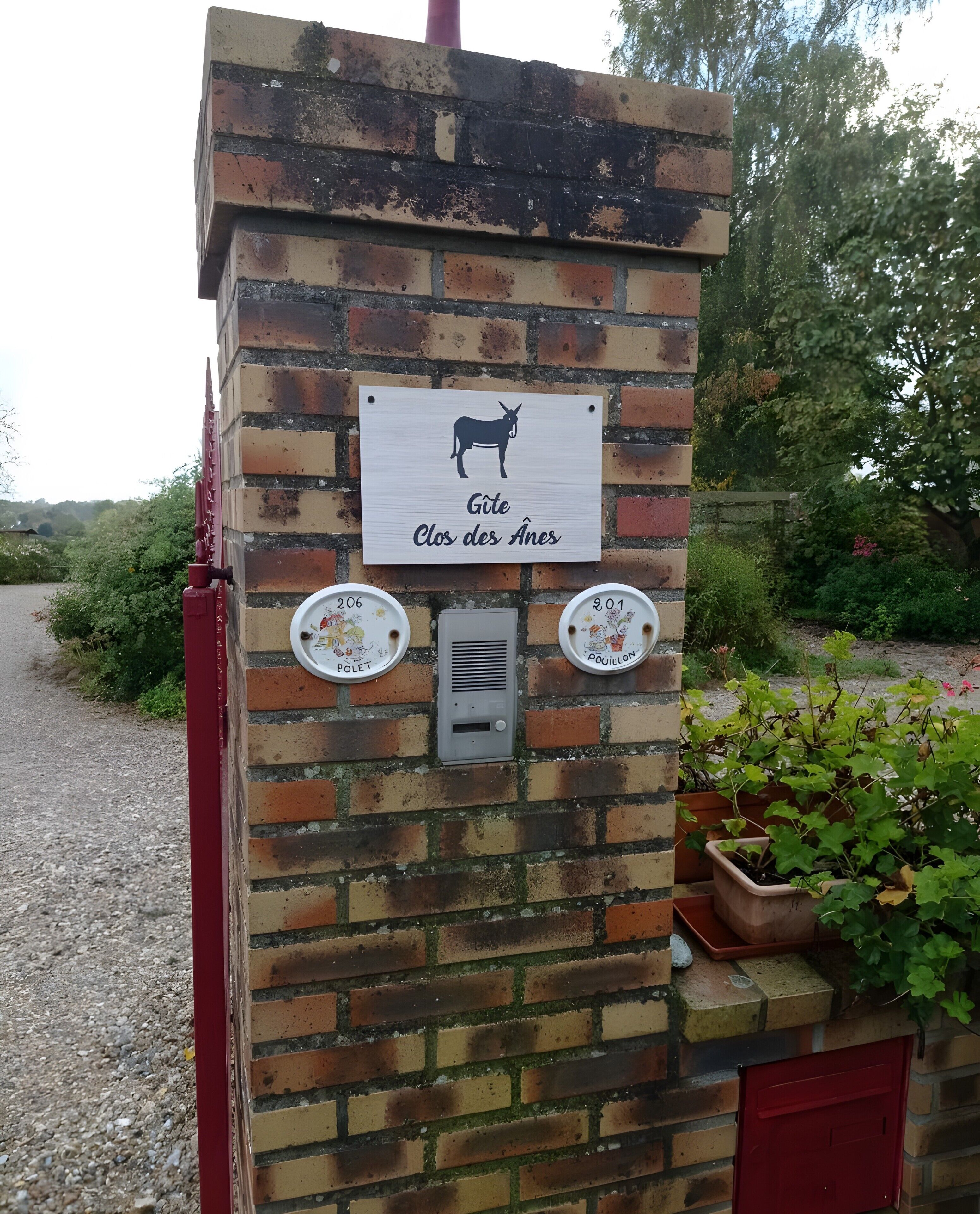 A brick structure with a donkey sign, two toilet labels, and a red door.