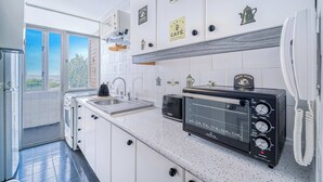 Ett modernt kök med vita skåp, en inbyggd ugn, en brödrost och en kaffebryggare.