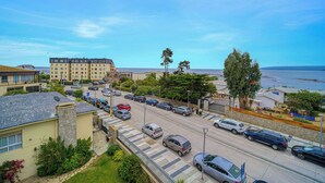 En kustväg med parkerade bilar, ett hotell och utsikt över havet.