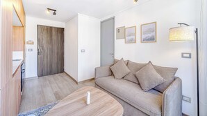 A modern living room with a sofa, a coffee table, and a door leading to another room. - Espacio Coventry II - 1D Wifi y AC (Ñuñoa)