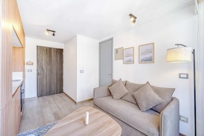 A modern living room with a sofa, a coffee table, and a door leading to another room. - Espacio Coventry II - 1D Wifi y AC (Ñuñoa)