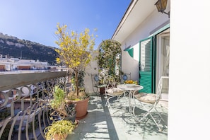 A balcony with potted plants, a table with chairs, and a view of the city. - Apartment 'Casa Beatrice' with Mountain View, Wi-Fi and Air Conditioning (Sorrento)