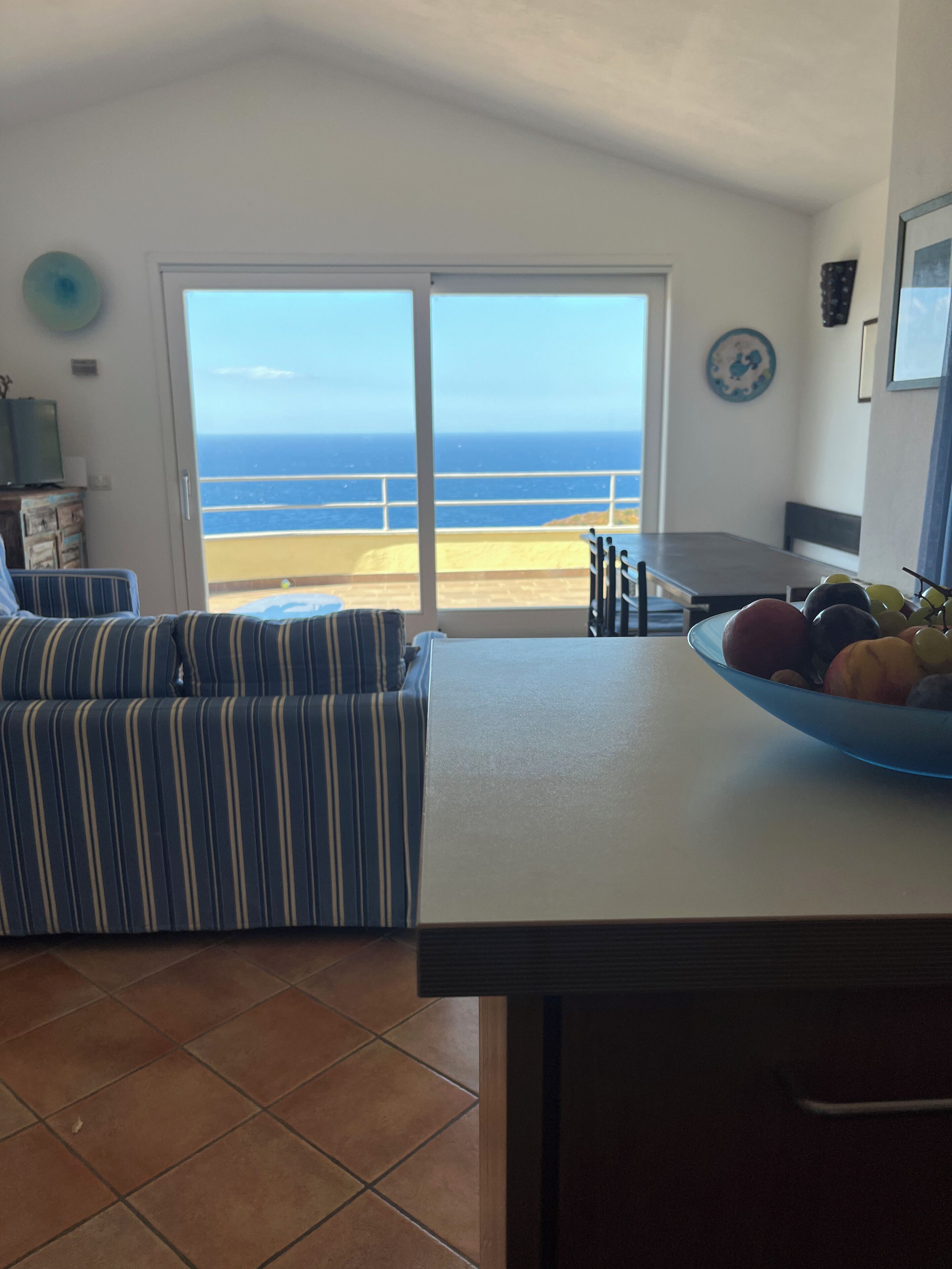 A kitchen with a view of the ocean, a dining table, and a sofa.