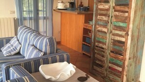 A living room with a striped sofa, a small table, and a rustic cabinet. - Villa tre fari all'Isola d'Elba (Colle D'orano)