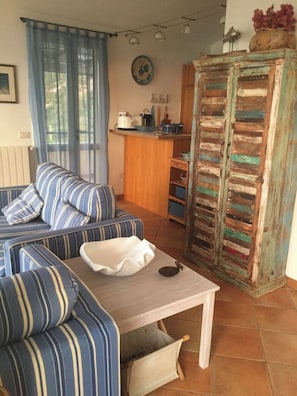 A living room with a striped sofa, a small table, and a rustic cabinet.