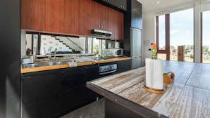 Una cocina moderna con armarios de madera oscura, electrodomésticos de acero inoxidable y una isla grande con encimera de madera.