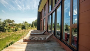 Un edificio moderno con ventanas amplias y una terraza de madera con bancos.