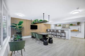 A modern kitchen with a central island, bar stools, and a dining area with green chairs. - Espacio Urbano- 3D, Vista 180° w/ Wifi (Ñuñoa)
