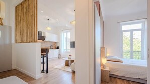 A modern apartment with a kitchen, dining area, and a bedroom with a large window. - Bright, modern 2-bedroom in city center (Hyères)