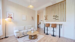A modern living room with a sofa, a round coffee table, and two bar stools. - Bright, modern 2-bedroom in city center (Hyères)