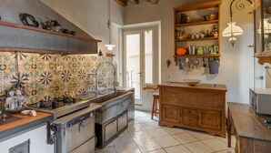 Een keuken met een betegelde achterwand, houten kastjes, een ingebouwde oven en een hangende lamp.