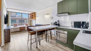 Een moderne keuken met een eethoek, een inbouwoven en een groot raam met uitzicht op een stadslandschap.