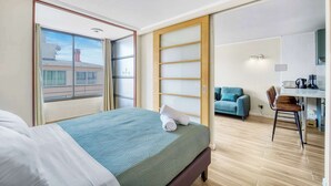 Een hotelkamer met een bed, een bureau, een stoel en uitzicht op buiten.
