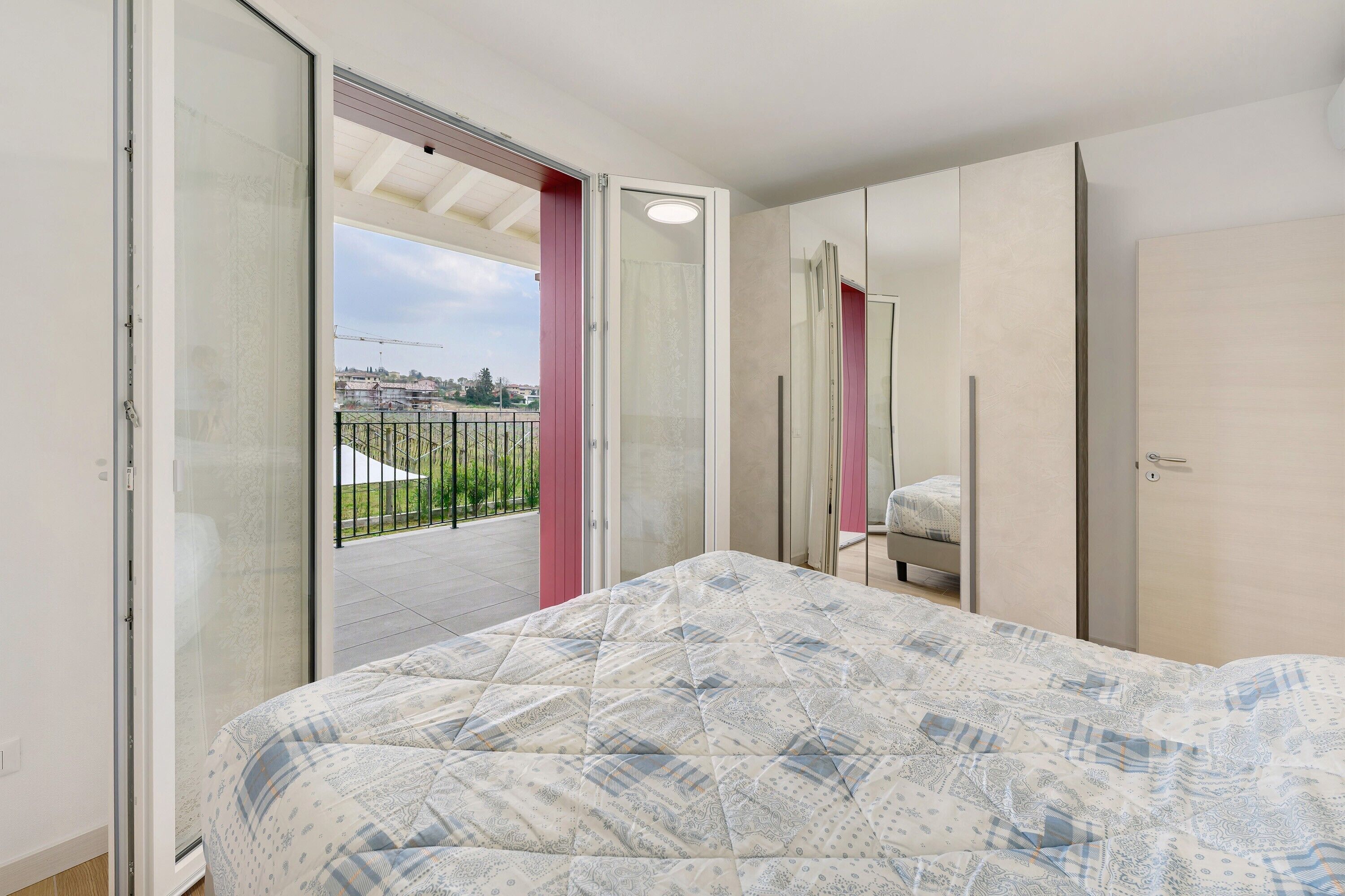 A bedroom with a bed, a sliding glass door leading to a balcony, and a wardrobe.